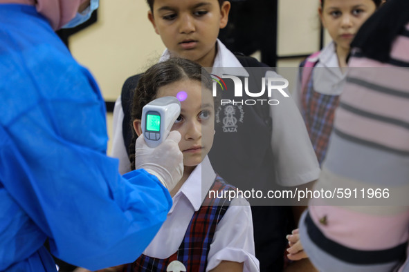 A Palestinian staff member checks a student temperature in the rosary sisters school gaza , on the first day of a new school year, as Palest...