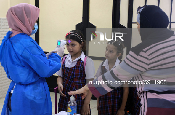 A Palestinian staff member checks a student temperature in the rosary sisters school gaza , on the first day of a new school year, as Palest...