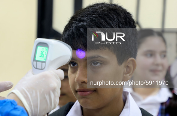 A Palestinian staff member checks a student temperature in the rosary sisters school gaza , on the first day of a new school year, as Palest...