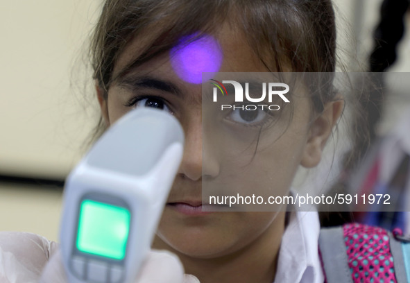 A Palestinian staff member checks a student temperature in the rosary sisters school gaza , on the first day of a new school year, as Palest...