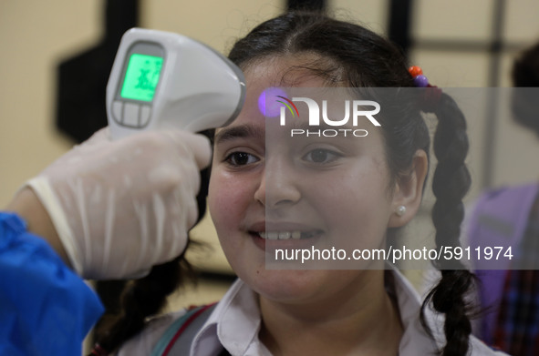 A Palestinian staff member checks a student temperature in the rosary sisters school gaza , on the first day of a new school year, as Palest...