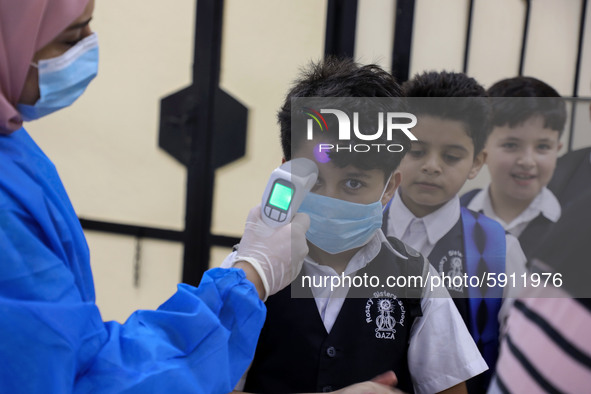 A Palestinian staff member checks a student temperature in the rosary sisters school gaza , on the first day of a new school year, as Palest...