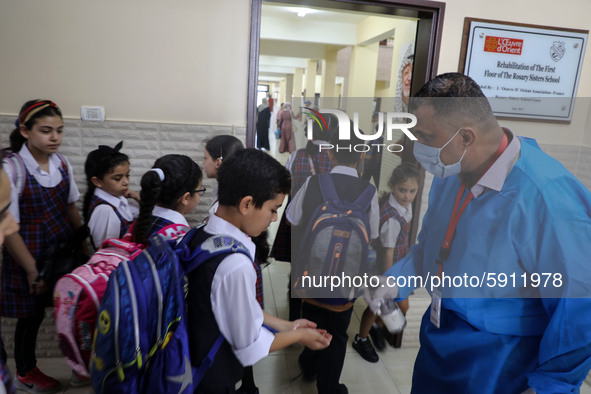 A Palestinian staff member provides disinfectant to a student in the rosary sisters school gaza , on the first day of a new school year, as...