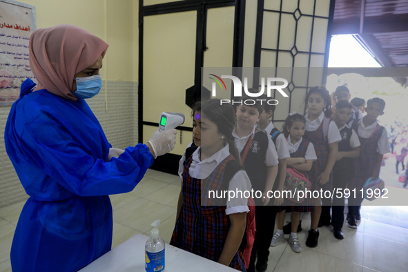 A Palestinian staff member checks a student temperature in the rosary sisters school gaza , on the first day of a new school year, as Palest...