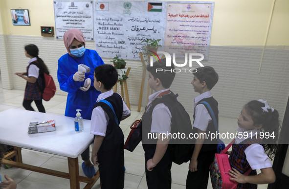 A Palestinian staff member checks a student temperature in the rosary sisters school gaza , on the first day of a new school year, as Palest...