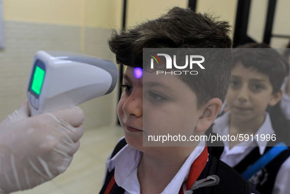 A Palestinian staff member checks a student temperature in the rosary sisters school gaza , on the first day of a new school year, as Palest...