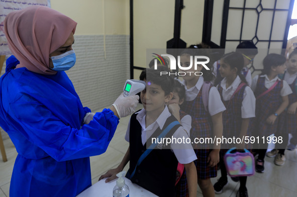 A Palestinian staff member checks a student temperature in the rosary sisters school gaza , on the first day of a new school year, as Palest...