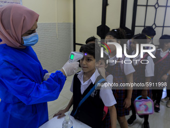 A Palestinian staff member checks a student temperature in the rosary sisters school gaza , on the first day of a new school year, as Palest...