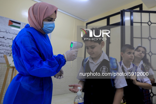 A Palestinian staff member checks a student temperature in the rosary sisters school gaza , on the first day of a new school year, as Palest...