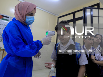 A Palestinian staff member checks a student temperature in the rosary sisters school gaza , on the first day of a new school year, as Palest...