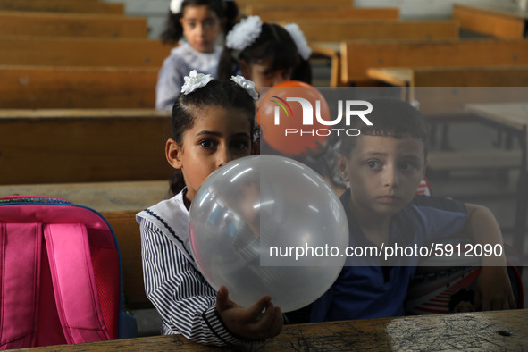 Palestinian students holding balloons sit in a classroom at a United Nations-run school as a new school year begins as Palestinians ease the...