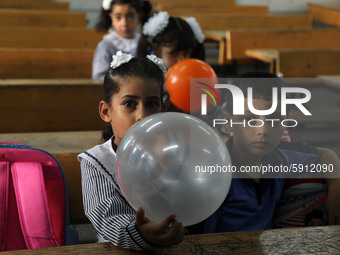 Palestinian students holding balloons sit in a classroom at a United Nations-run school as a new school year begins as Palestinians ease the...