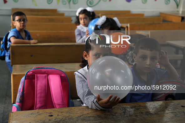 Palestinian students holding balloons sit in a classroom at a United Nations-run school as a new school year begins as Palestinians ease the...