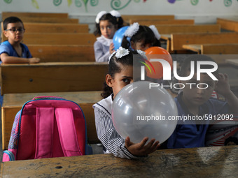 Palestinian students holding balloons sit in a classroom at a United Nations-run school as a new school year begins as Palestinians ease the...