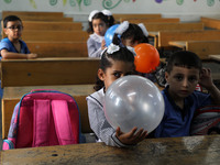 Palestinian students holding balloons sit in a classroom at a United Nations-run school as a new school year begins as Palestinians ease the...