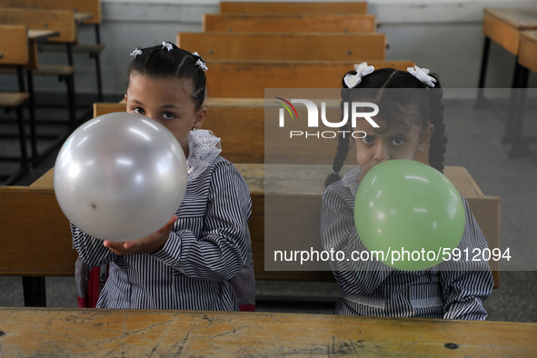 Palestinian students holding balloons sit in a classroom at a United Nations-run school as a new school year begins as Palestinians ease the...