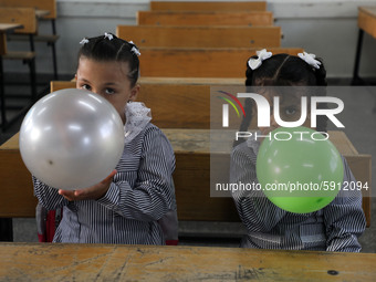 Palestinian students holding balloons sit in a classroom at a United Nations-run school as a new school year begins as Palestinians ease the...