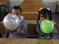 Palestinian students holding balloons sit in a classroom at a United Nations-run school as a new school year begins as Palestinians ease the...