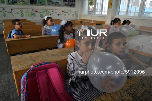 Palestinian students holding balloons sit in a classroom at a United Nations-run school as a new school year begins as Palestinians ease the...