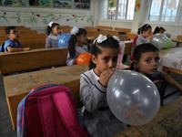 Palestinian students holding balloons sit in a classroom at a United Nations-run school as a new school year begins as Palestinians ease the...