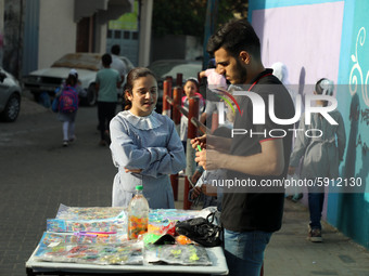 Palestinian students buy from a street vendor outside a United-Nations run school as a new school year begins as Palestinians ease the coron...