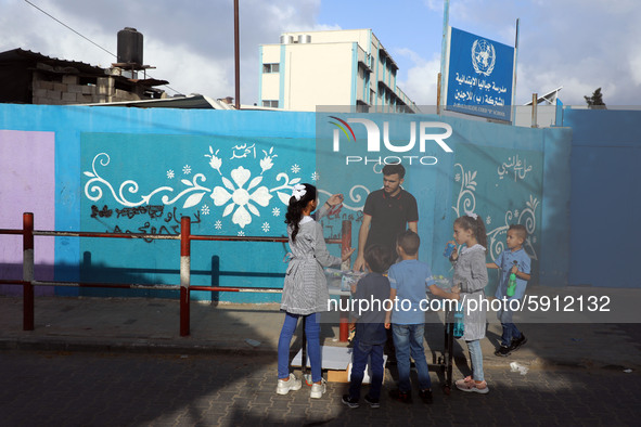 Palestinian students buy from a street vendor outside a United-Nations run school as a new school year begins as Palestinians ease the coron...