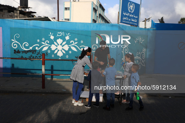 Palestinian students buy from a street vendor outside a United-Nations run school as a new school year begins as Palestinians ease the coron...