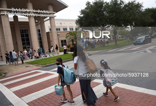 A mother walks her children to school on the first day of in-person classes in Orange County at Baldwin Park Elementary School on August 21,...