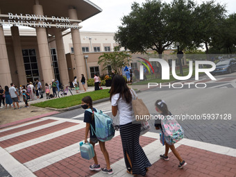 A mother walks her children to school on the first day of in-person classes in Orange County at Baldwin Park Elementary School on August 21,...