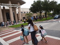 A mother walks her children to school on the first day of in-person classes in Orange County at Baldwin Park Elementary School on August 21,...