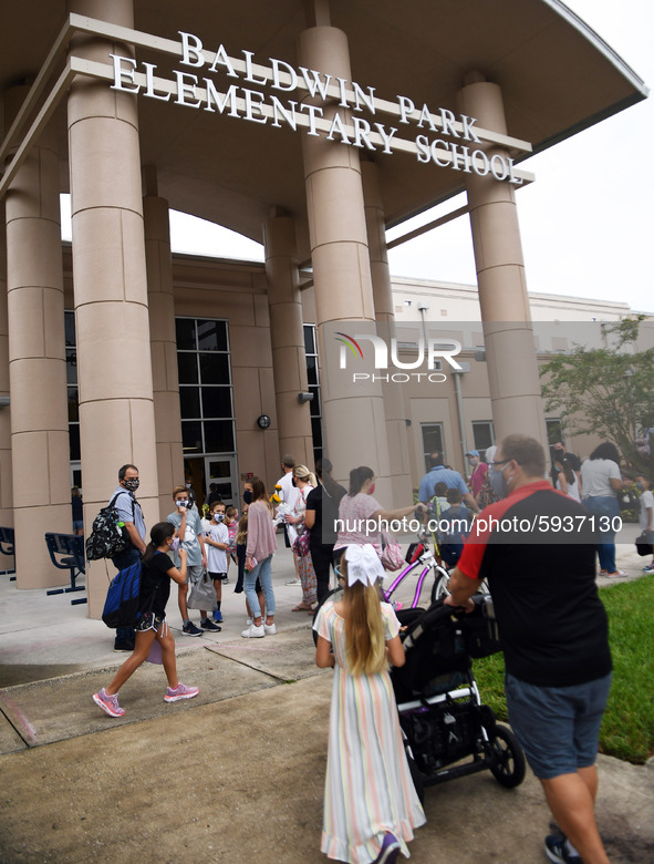 Parents walk their children to school on the first day of in-person classes in Orange County at Baldwin Park Elementary School on August 21,...