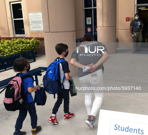 A  school employee escorts children as they return to school on the first day of in-person classes in Orange County at Baldwin Park Elementa...