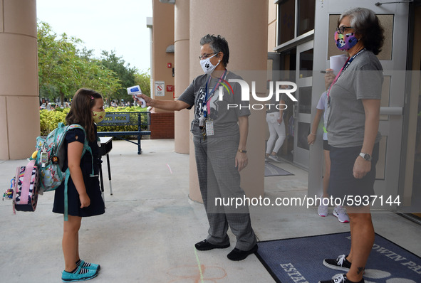 A school employee checks the temperature of a student as she returns to school on the first day of in-person classes in Orange County at Bal...