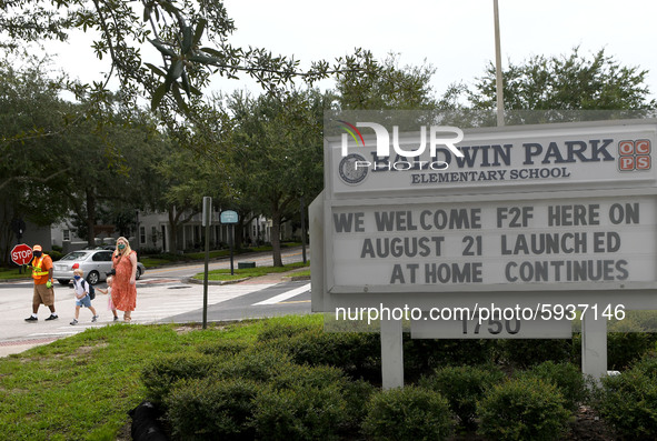 A mother walks her children to school on the first day of in-person classes in Orange County at Baldwin Park Elementary School on August 21,...