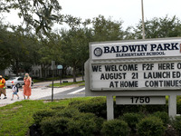 A mother walks her children to school on the first day of in-person classes in Orange County at Baldwin Park Elementary School on August 21,...