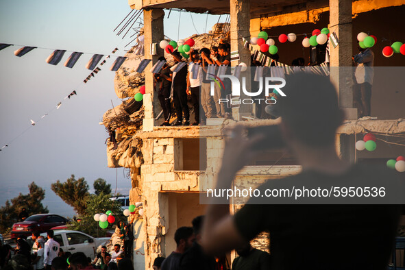 Syrians demonstrate in an anti-Assad demonstration near the rubble of a building that was hit in a previous bombing and decorated with the f...