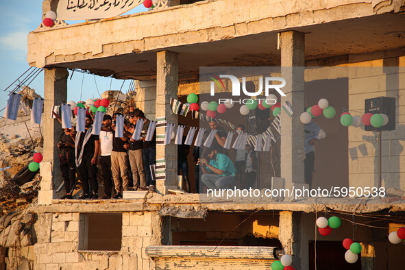 Syrians demonstrate in an anti-Assad demonstration near the rubble of a building that was hit in a previous bombing and decorated with the f...