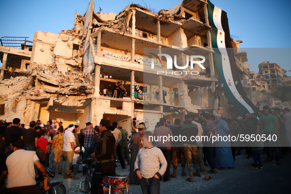 Syrians demonstrate in an anti-Assad demonstration near the rubble of a building that was hit in a previous bombing and decorated with the f...