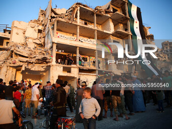 Syrians demonstrate in an anti-Assad demonstration near the rubble of a building that was hit in a previous bombing and decorated with the f...