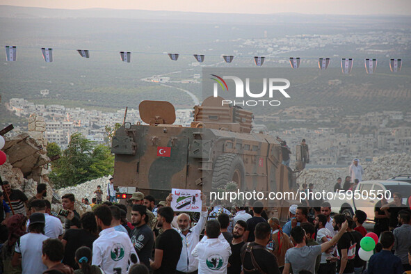 A Turkish military vehicle passes in front of a gathering of Syrians in an anti-Assad demonstration in Jabal al-Arbaeen in the town of Jeric...