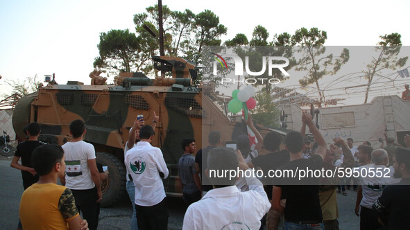 A Turkish military vehicle passes in front of a gathering of Syrians in an anti-Assad demonstration in Jabal al-Arbaeen in the town of Jeric...