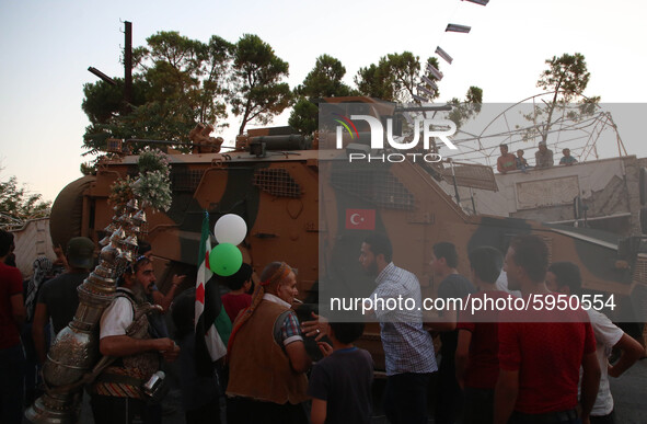 A Turkish military vehicle passes in front of a gathering of Syrians in an anti-Assad demonstration in Jabal al-Arbaeen in the town of Jeric...