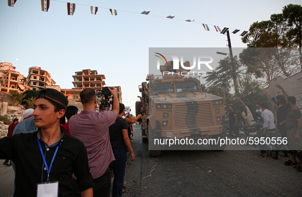 A Turkish military vehicle passes in front of a gathering of Syrians in an anti-Assad demonstration in Jabal al-Arbaeen in the town of Jeric...