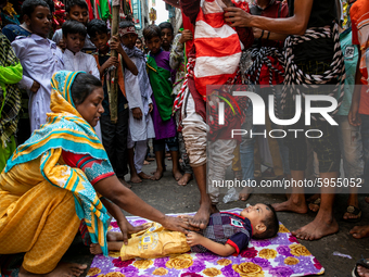 A child is laid down in front of the procession to perform a traditional act to get a better life and the future in Dhaka, Bangladesh, on Au...