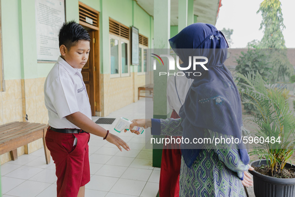 A teacher check body temperature of a student at Candirejo Elementary School, Semarang Regency, Central Java, Indonesia, on September 1, 202...