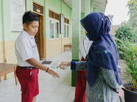 A teacher check body temperature of a student at Candirejo Elementary School, Semarang Regency, Central Java, Indonesia, on September 1, 202...