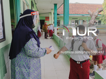 A teacher check body temperature of a student at Candirejo Elementary School, Semarang Regency, Central Java, Indonesia, on September 1, 202...