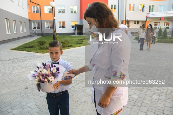 Physician measures temperature First grader during the ceremony on the occasion of the beginning of the new school year against the backgrou...