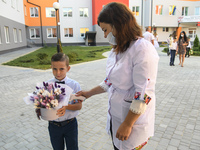 Physician measures temperature First grader during the ceremony on the occasion of the beginning of the new school year against the backgrou...