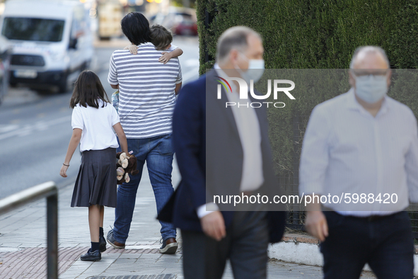 A man carrying his son and daughter during the first day of school on September 10, 2020 in Granada, Spain.  